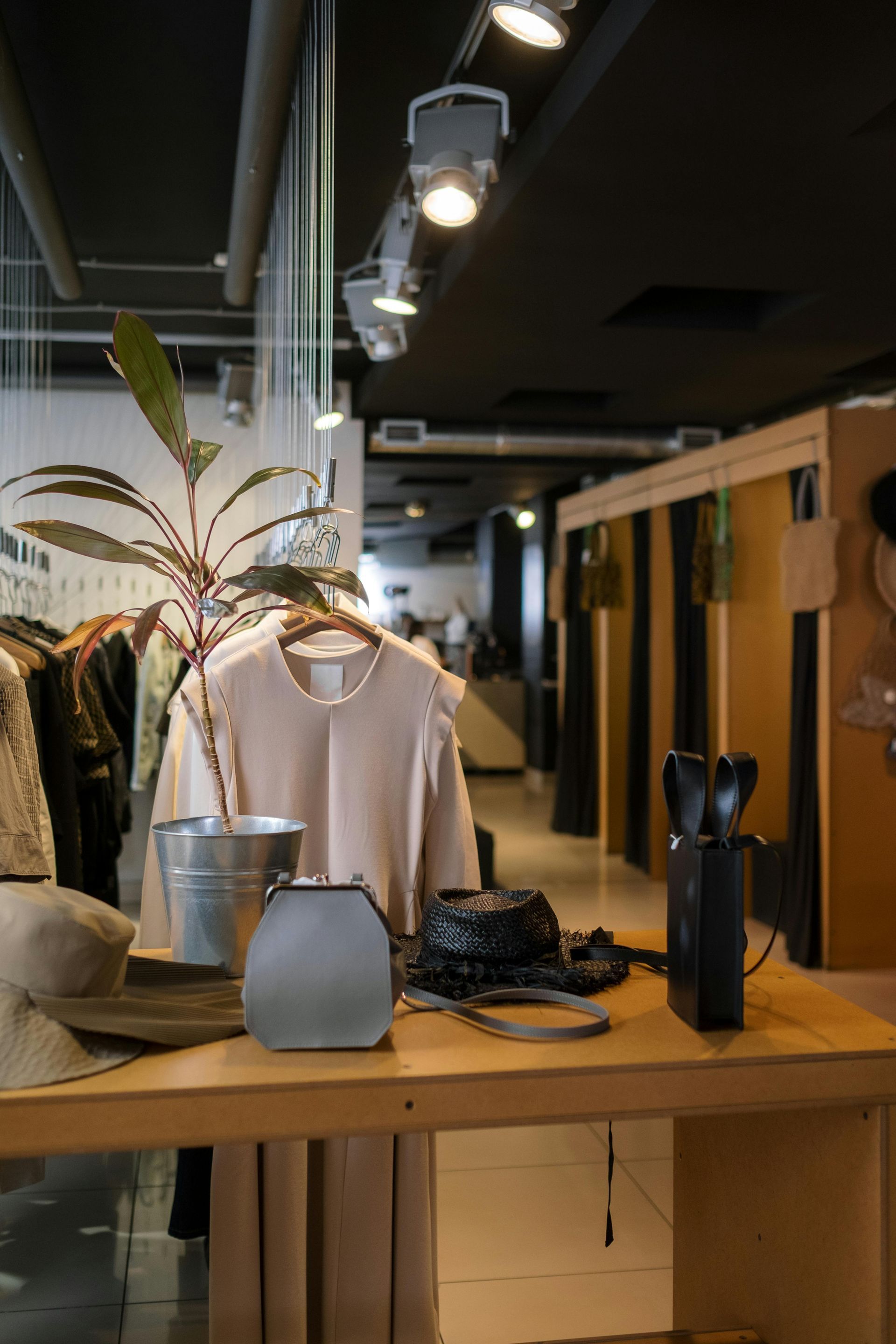 A table in a store with clothes and a plant on it.