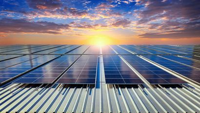Paneles solares en un tejado, que reflejan el brillante sol poniente, con un cielo nublado.