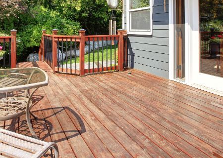 A wooden deck with a table and chairs in front of a house.