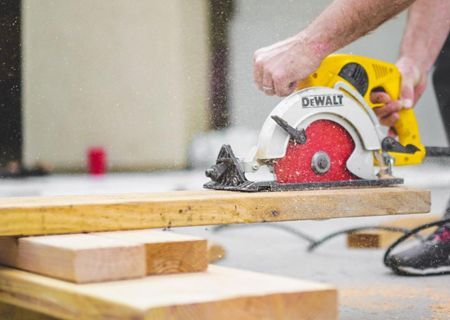 A man is using a circular saw to cut a piece of wood.