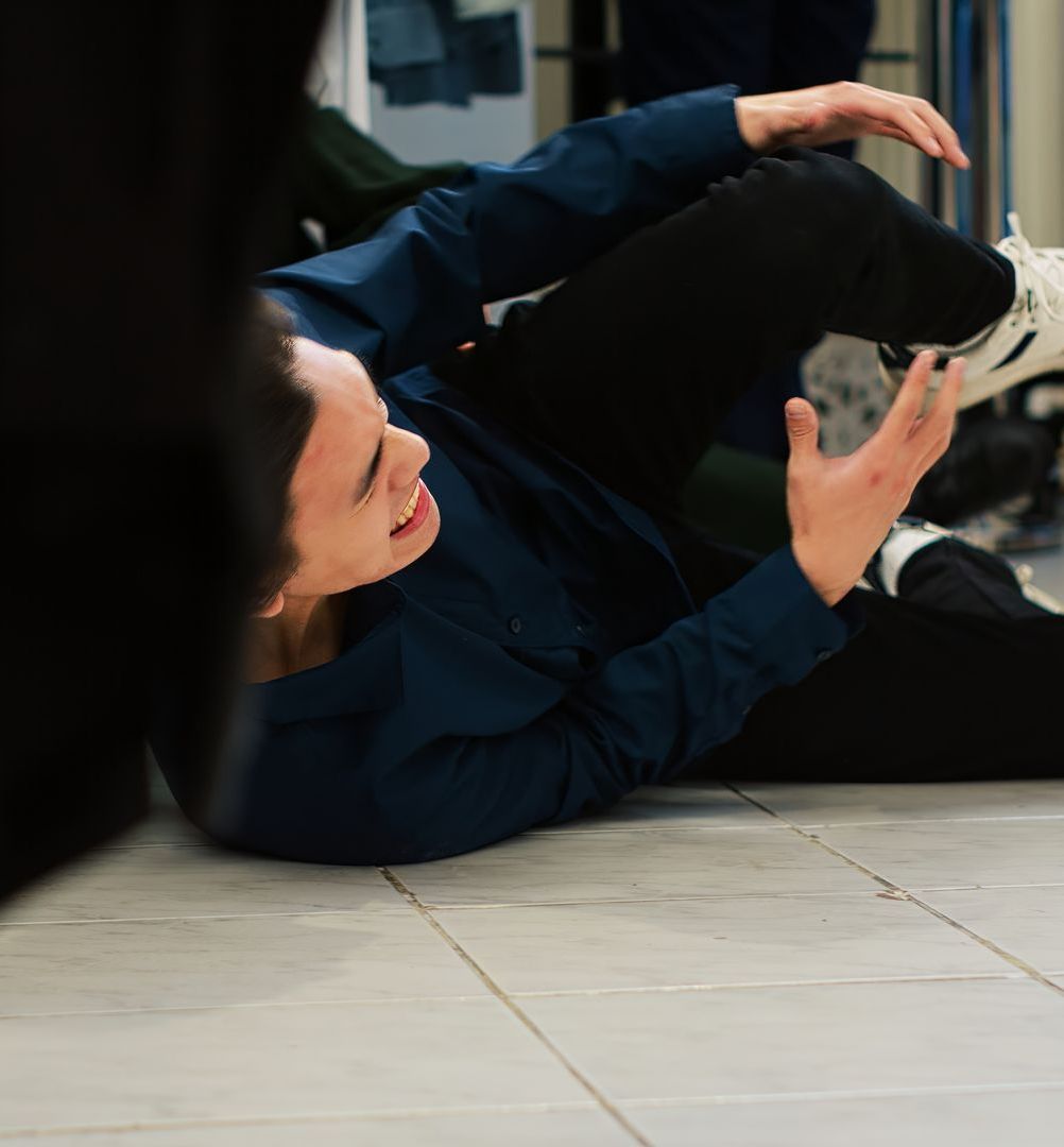 A man in a blue shirt is laying on the floor and smiling