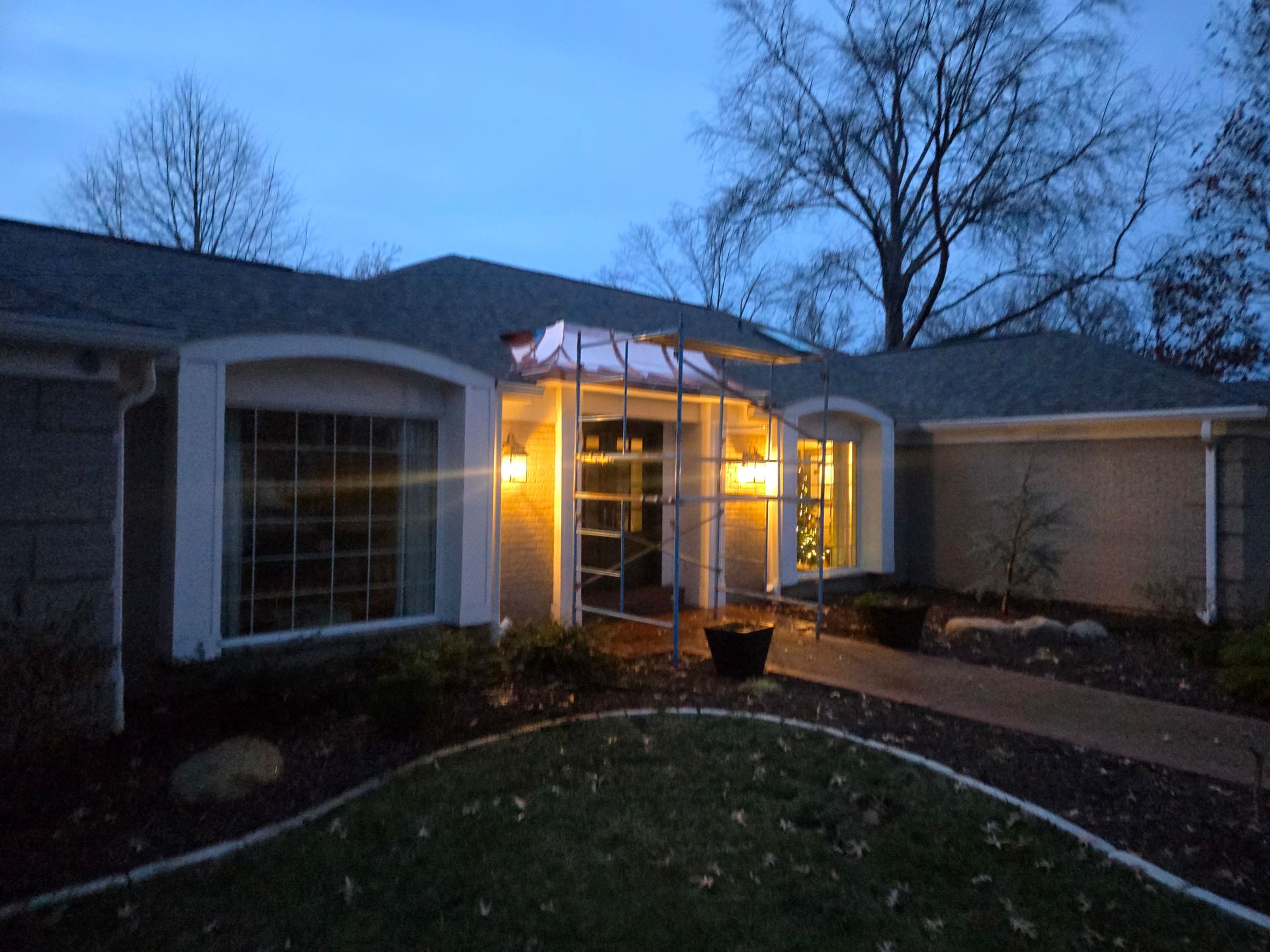 Rain pouring off a brown tiled roof into a white gutter on a cloudy day.