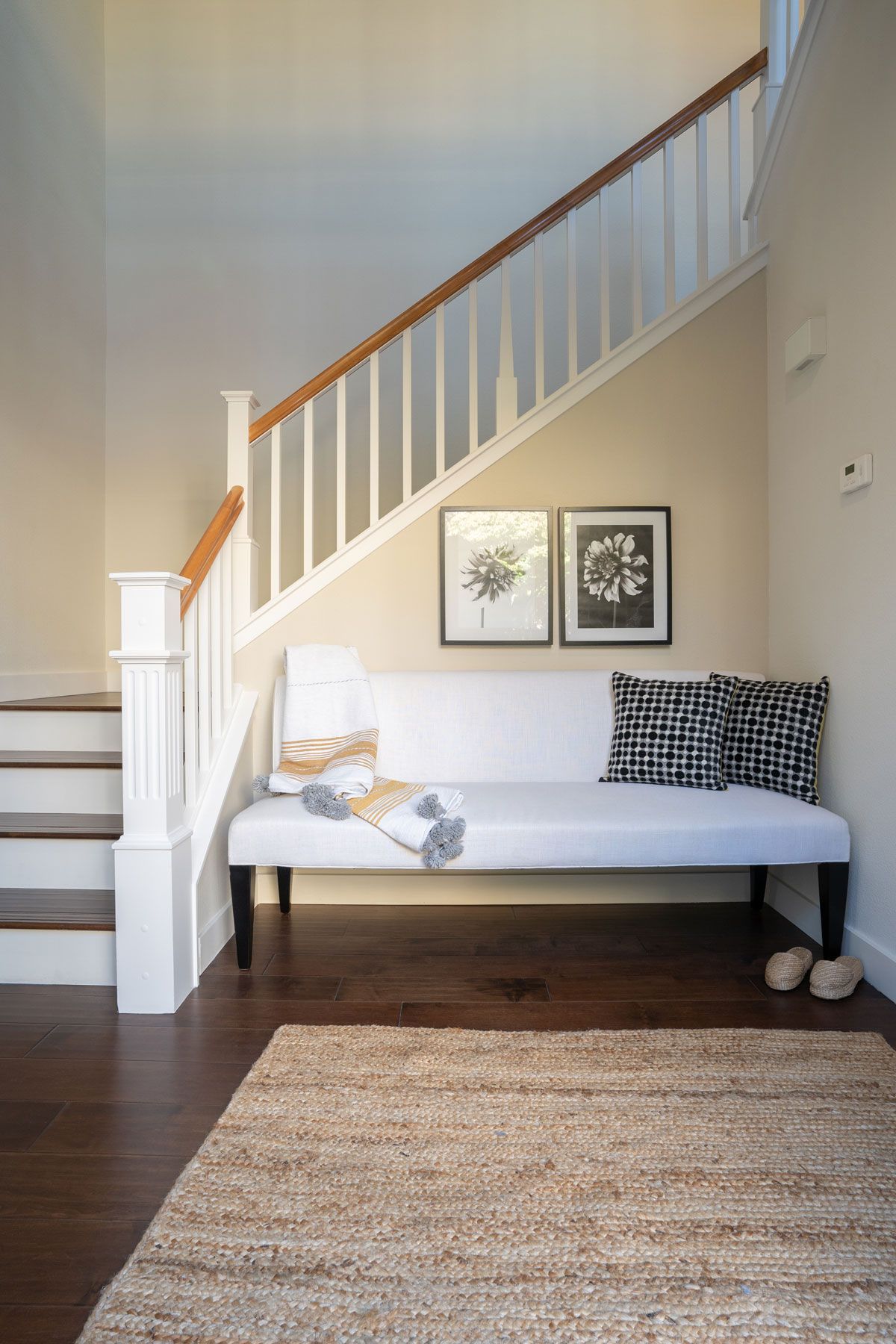 There is a bench under the stairs in the hallway.