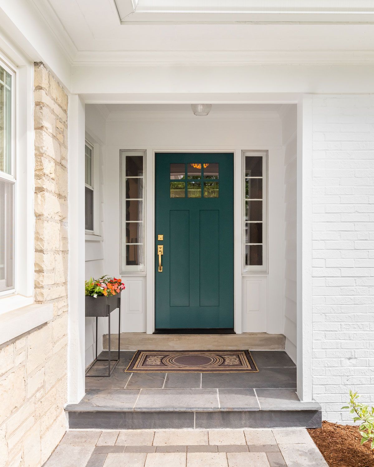 The front door of a white brick house with a green door.