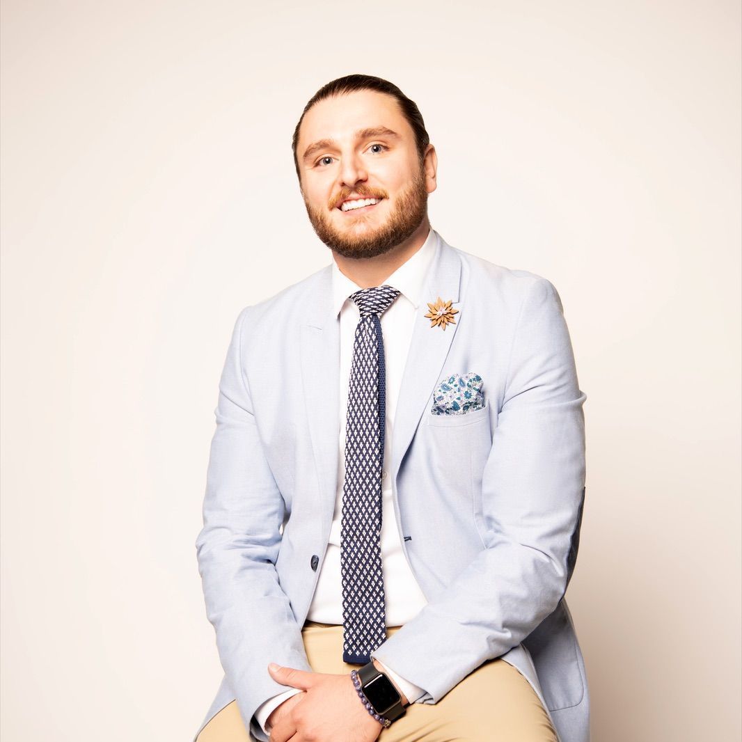 A man in a suit and tie is sitting on a stool