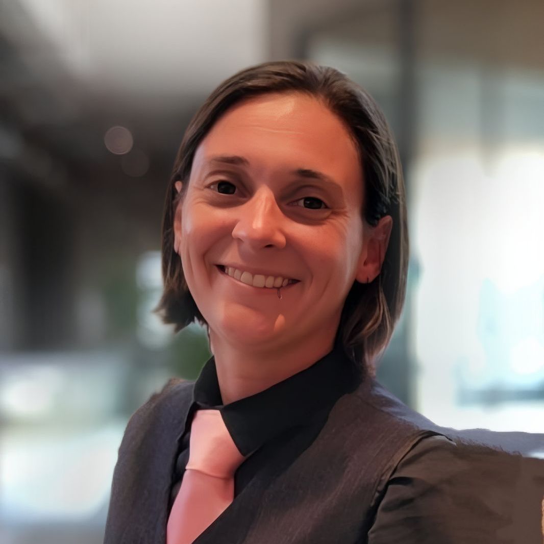 A woman wearing a black shirt and a pink tie smiles for the camera