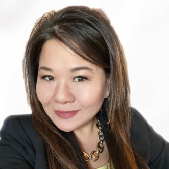 A woman wearing a black jacket and a gold necklace smiles for the camera.