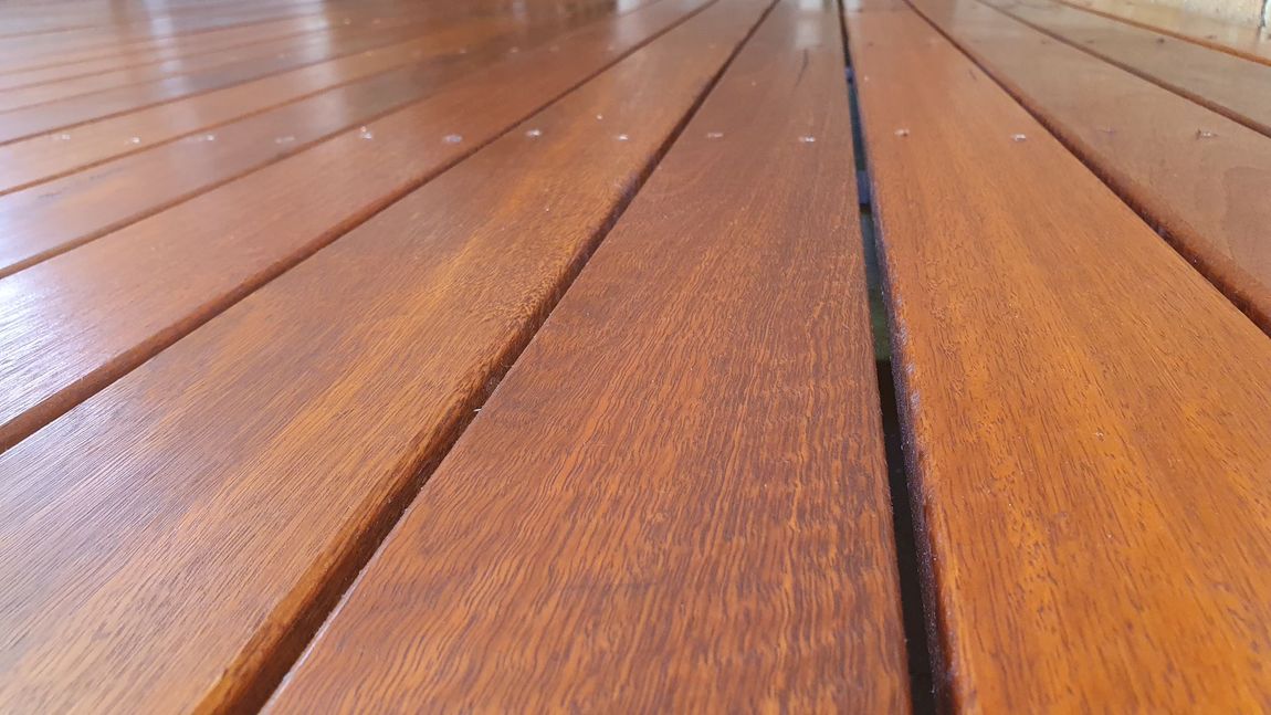 Close-up of a wood deck with a shiny, reddish-brown finish.