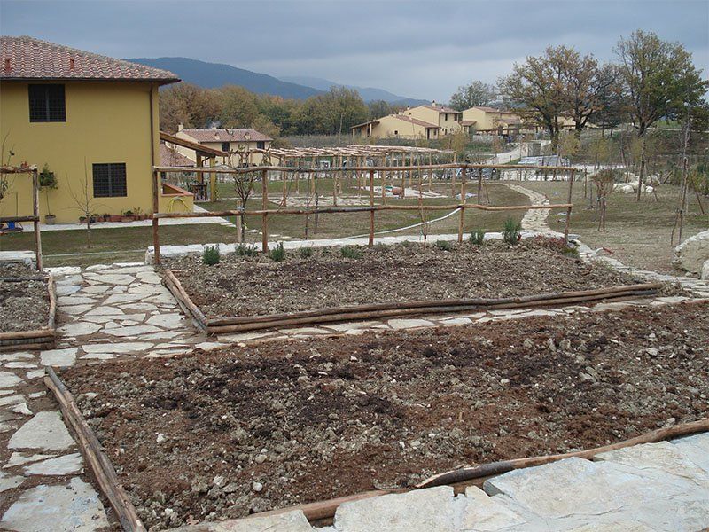 Un giardino con una casa gialla sullo sfondo