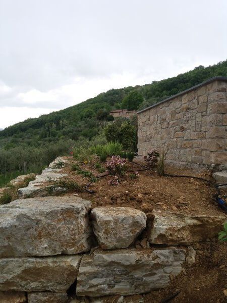 Un muro di pietra è posto in cima a una collina di terra.