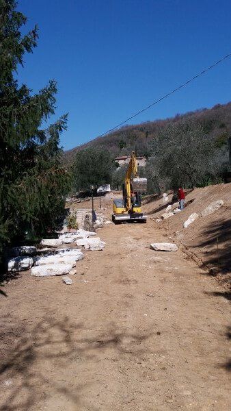 Un escavatore giallo sta percorrendo una strada sterrata.