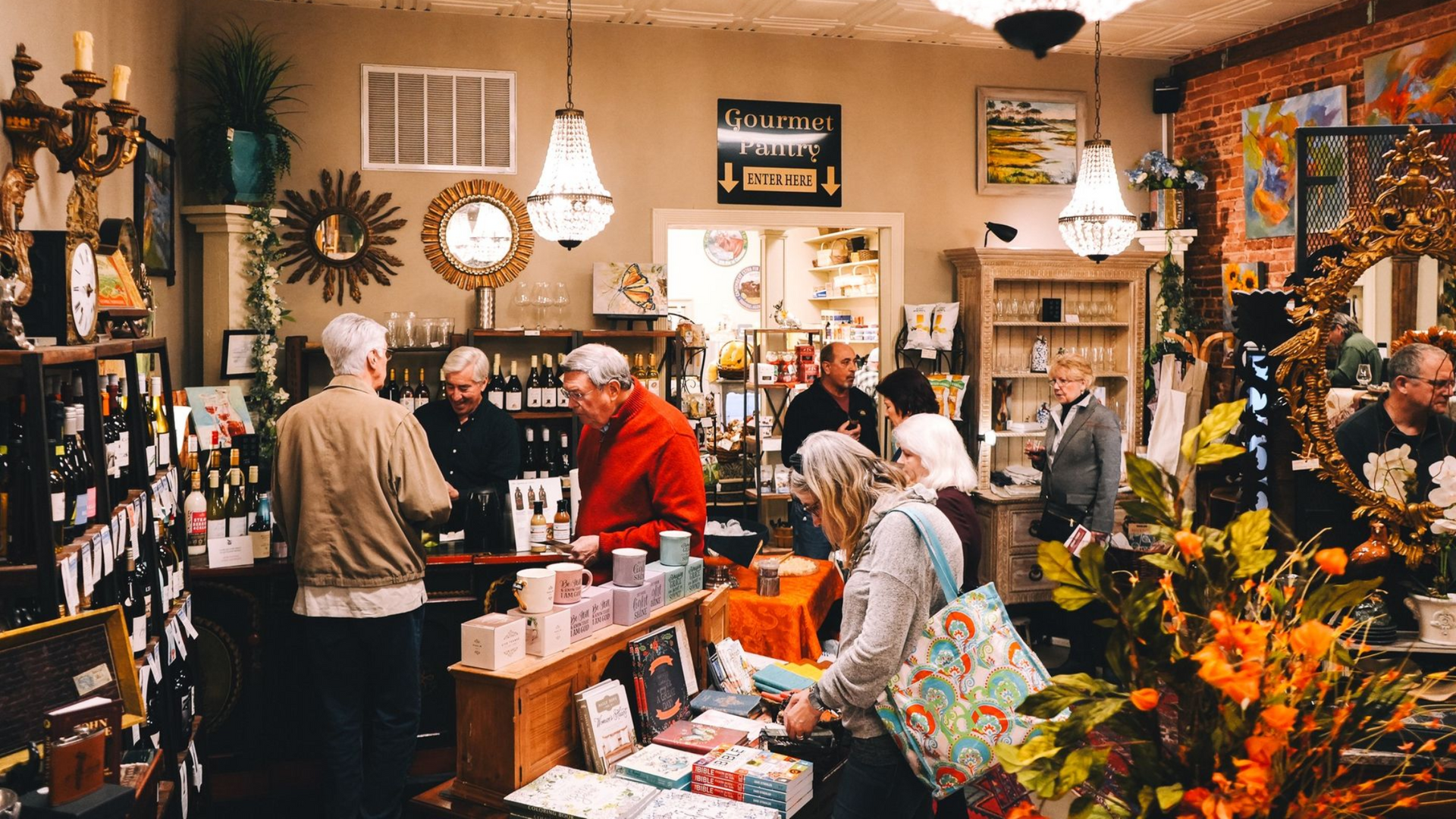 People browse inside a shop filled with merchandise, including wine and decor.