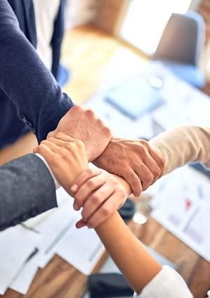 Hands clasped together in a team huddle, symbolizing unity and collaboration.