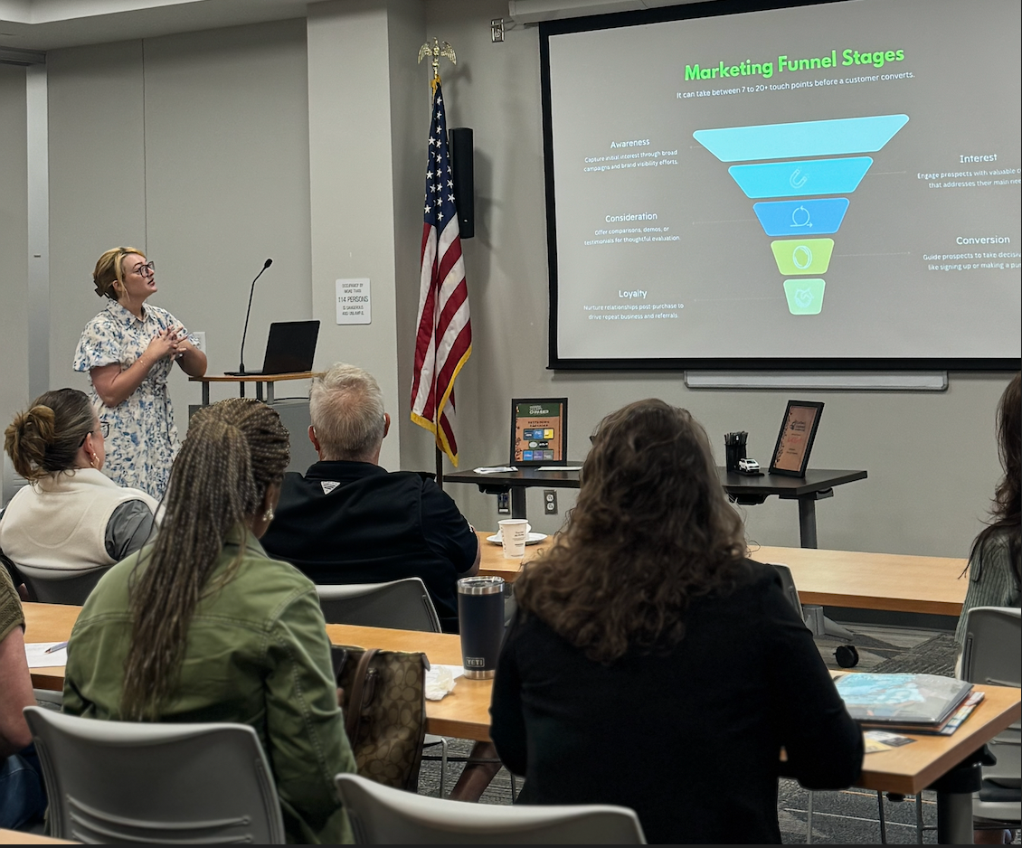 Two men shaking hands in a business meeting, others seated around a table.