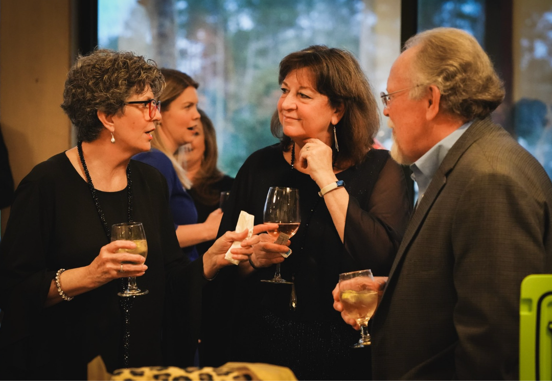 Woman working on laptop, analyzing charts and using a calculator at a desk in a sunny office.