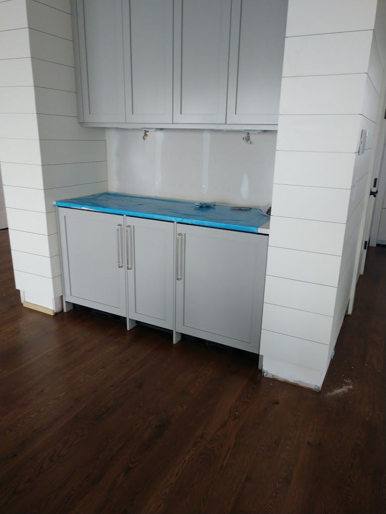 A kitchen with white cabinets and a wooden floor