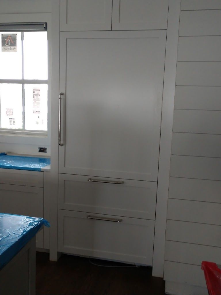 A white refrigerator is built into a wall in a kitchen.