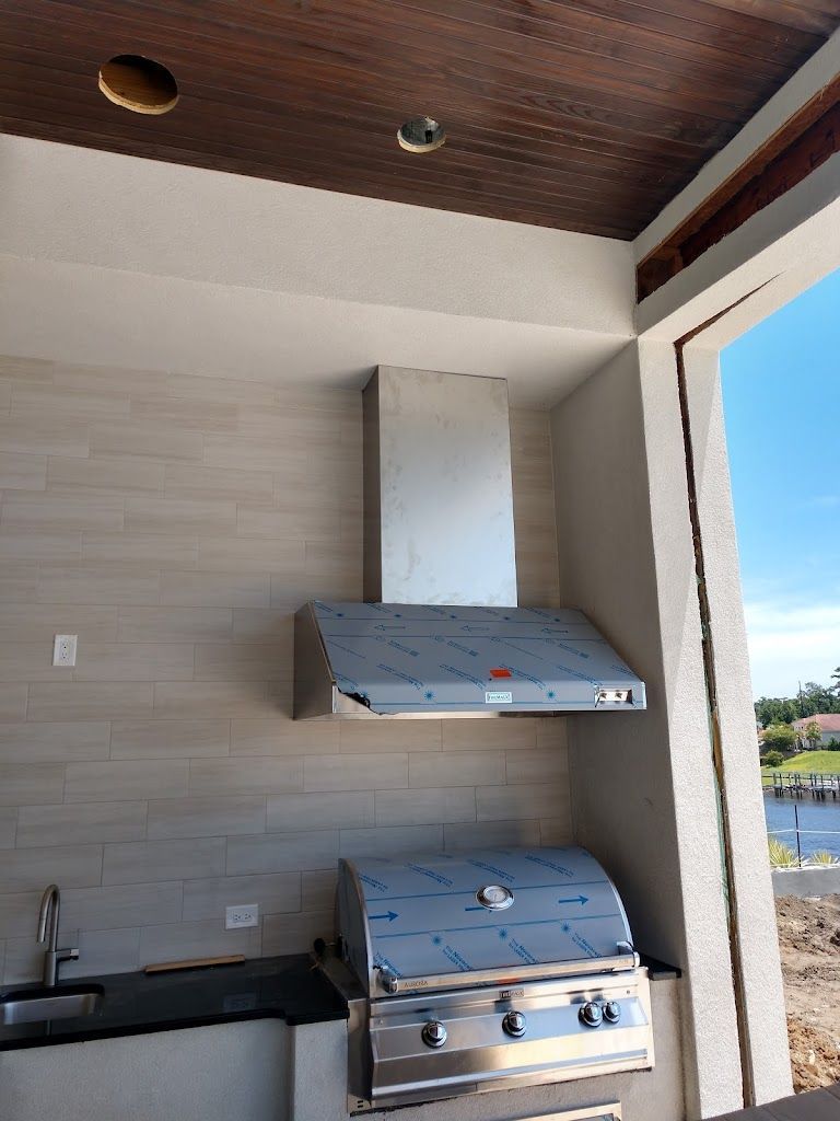 A kitchen with a stainless steel hood and a grill.
