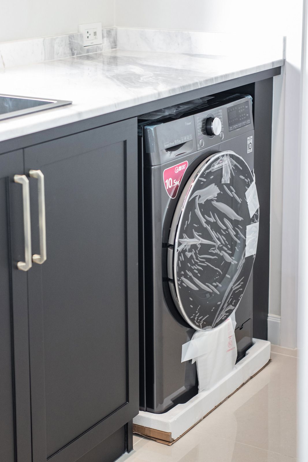 A washing machine is sitting under a sink in a laundry room.