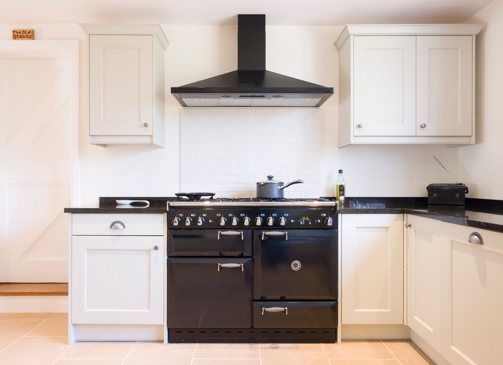 A kitchen with white cabinets and a wooden hood above the stove