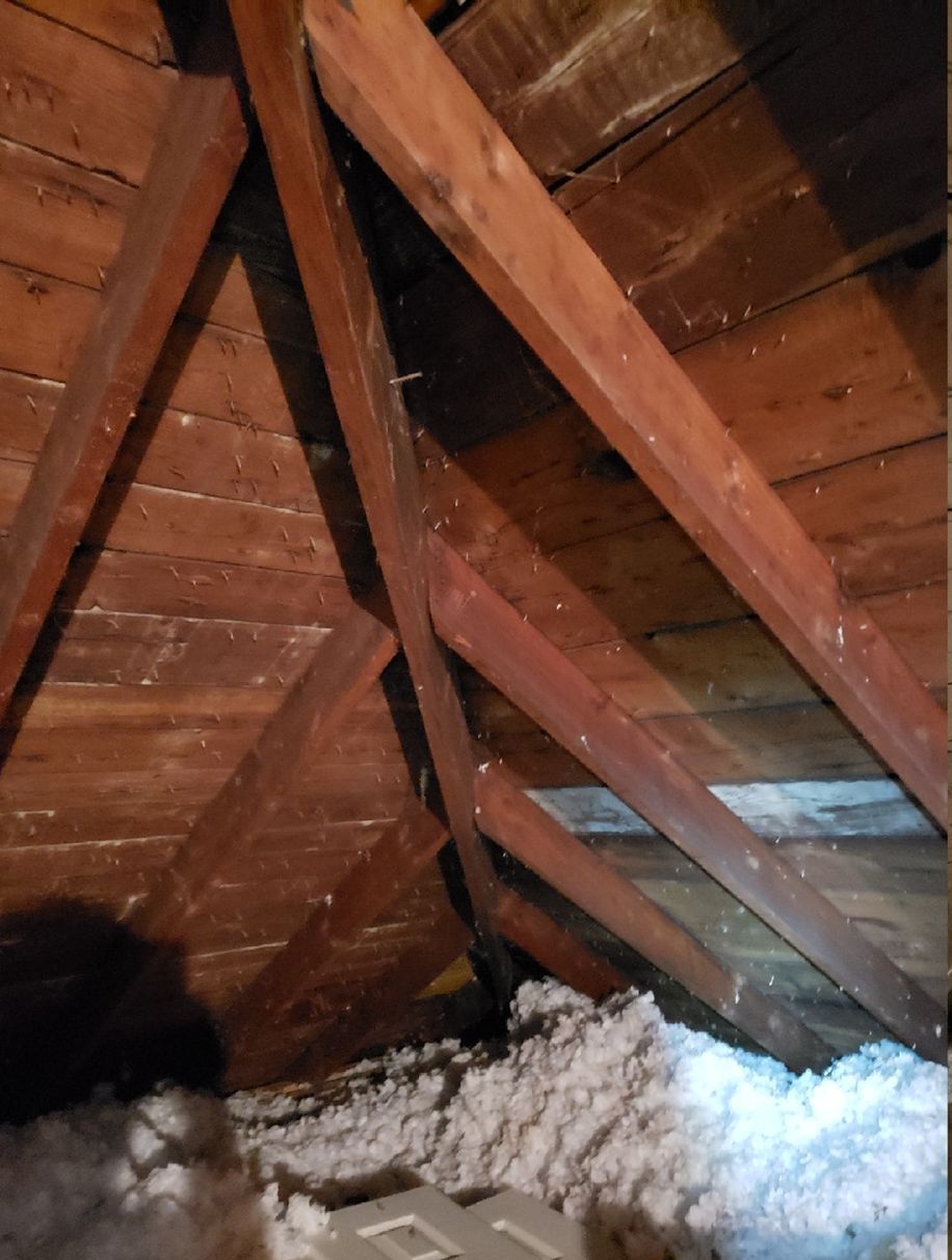An attic with wooden beams and insulation in it