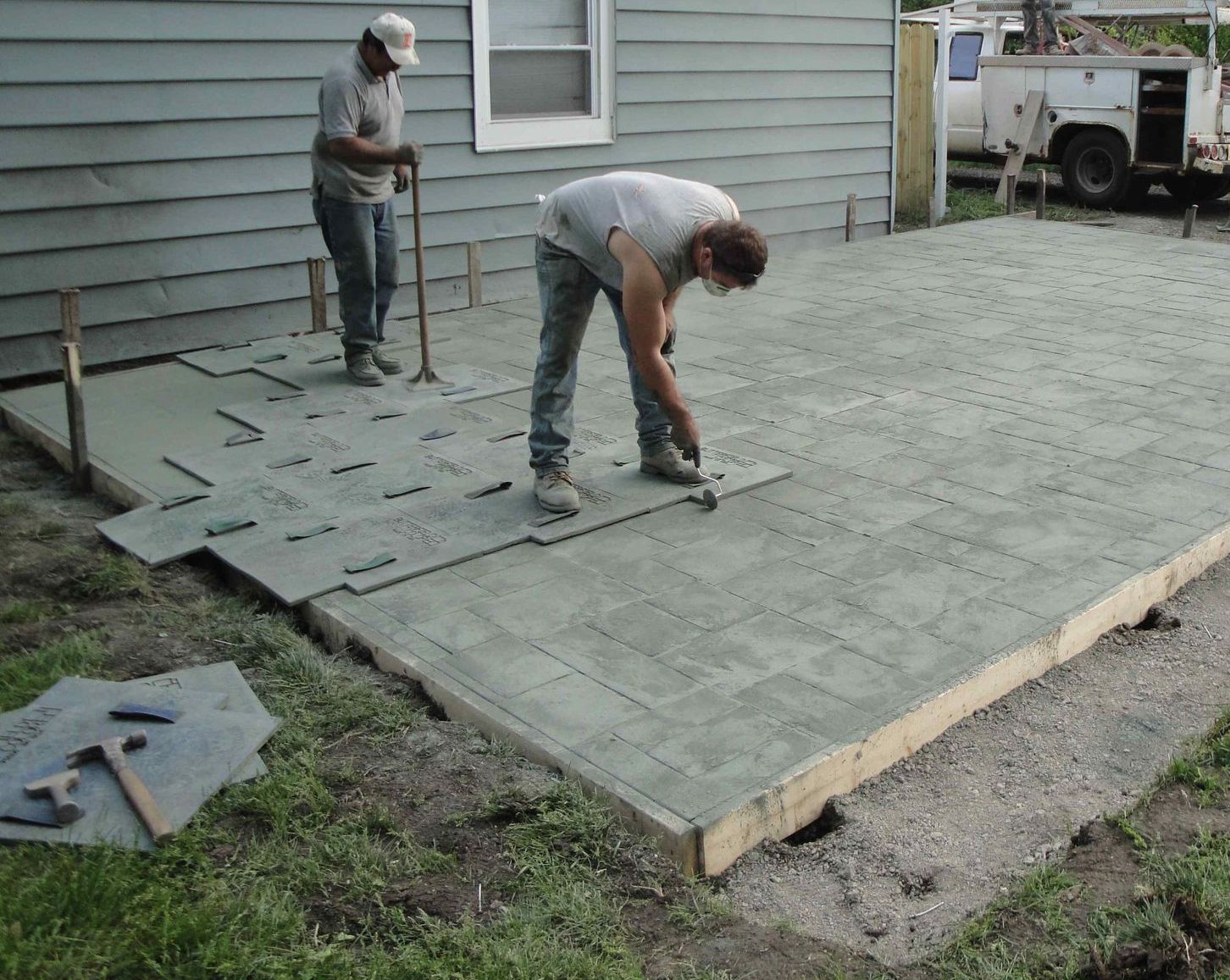 Workers Installing Stamped Concrete Patio In Backyard