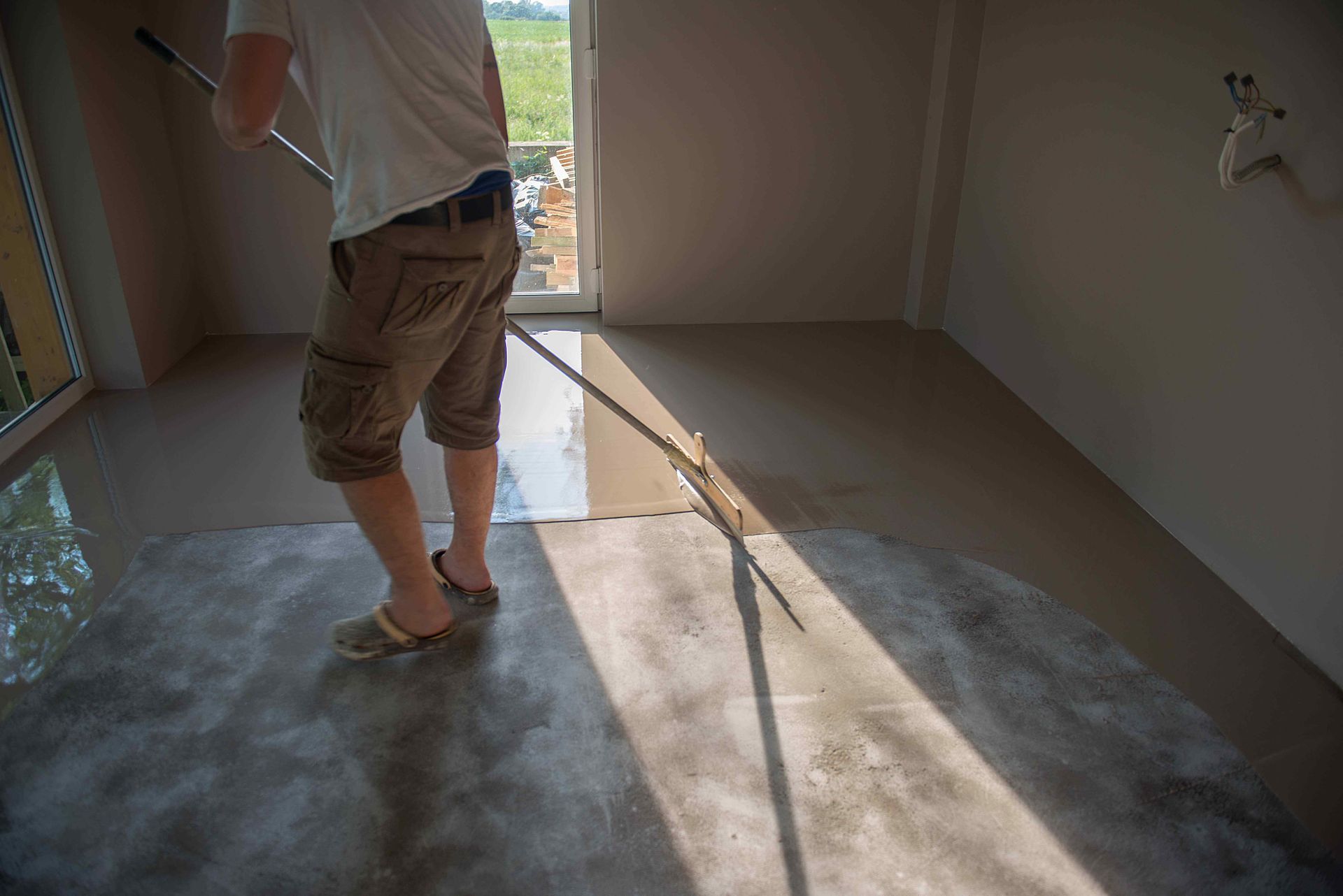 Technician Applying Protective Coating To Concrete Floor