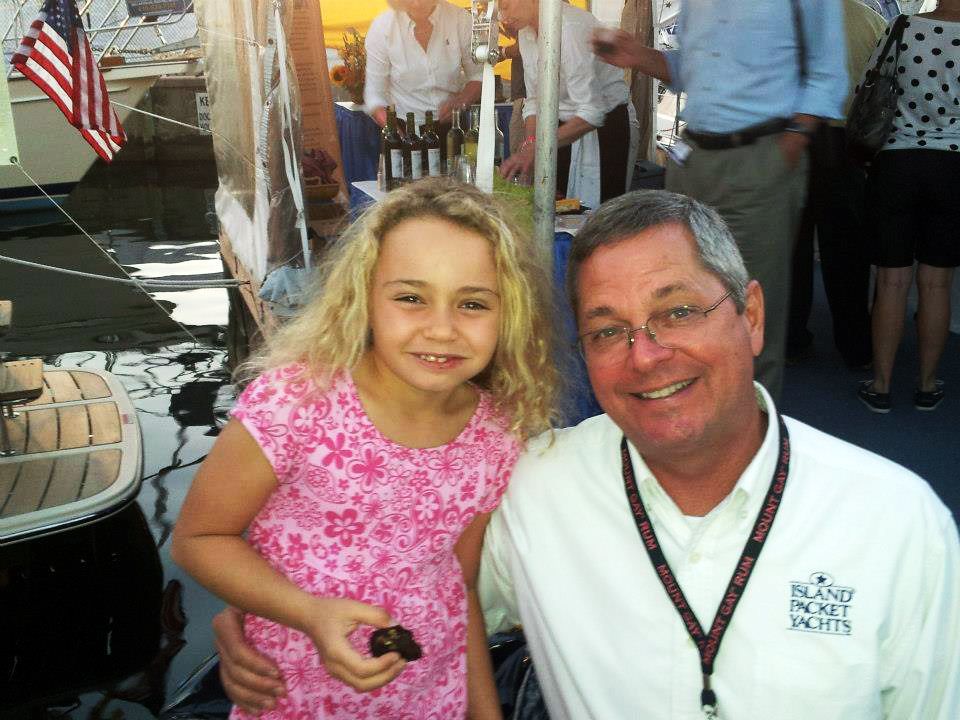 A man and a little girl pose for a picture and the man is wearing a lanyard with a crown on it