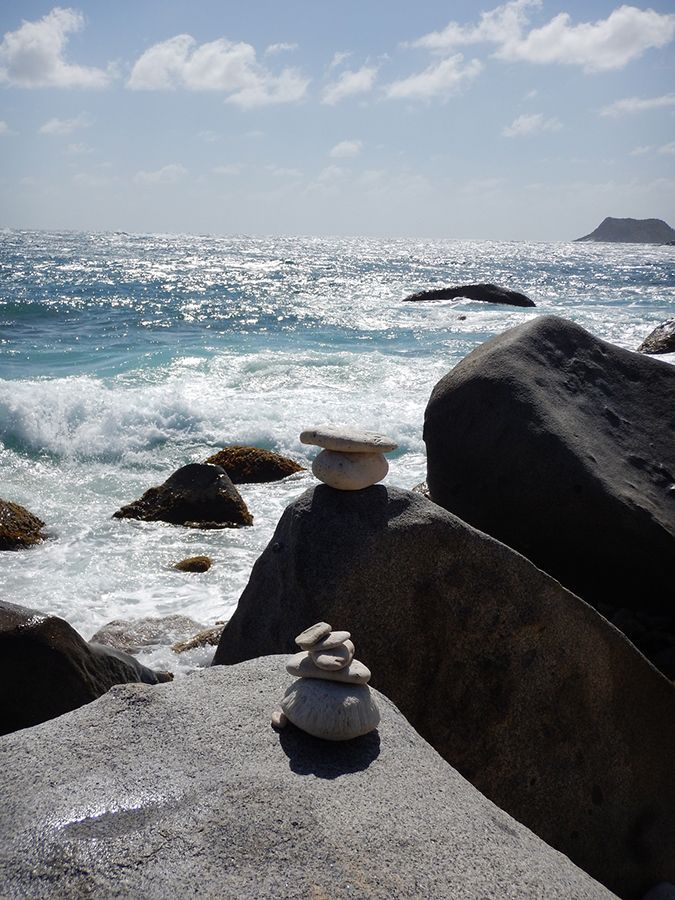 A stack of rocks sits on a rock near the ocean