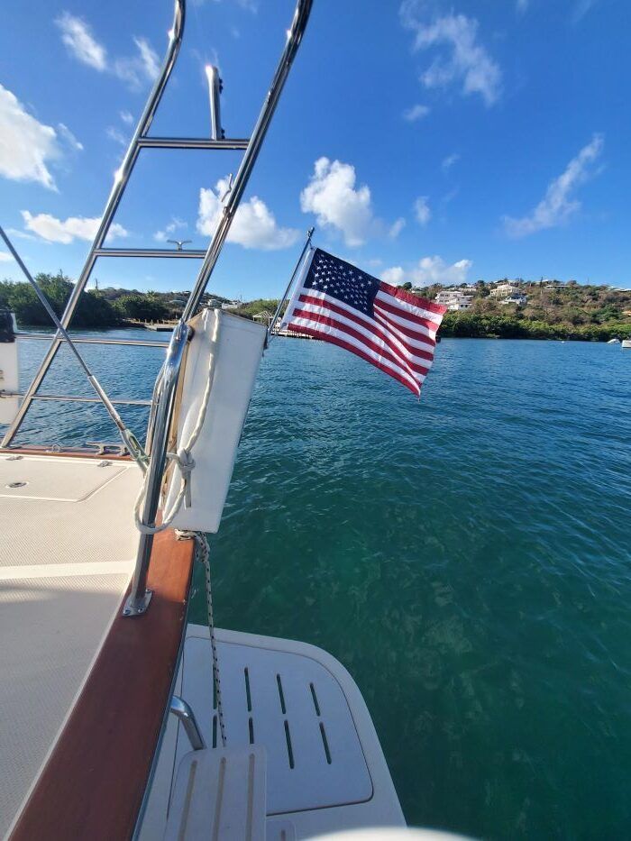 An american flag is hanging from the side of a boat in the water.