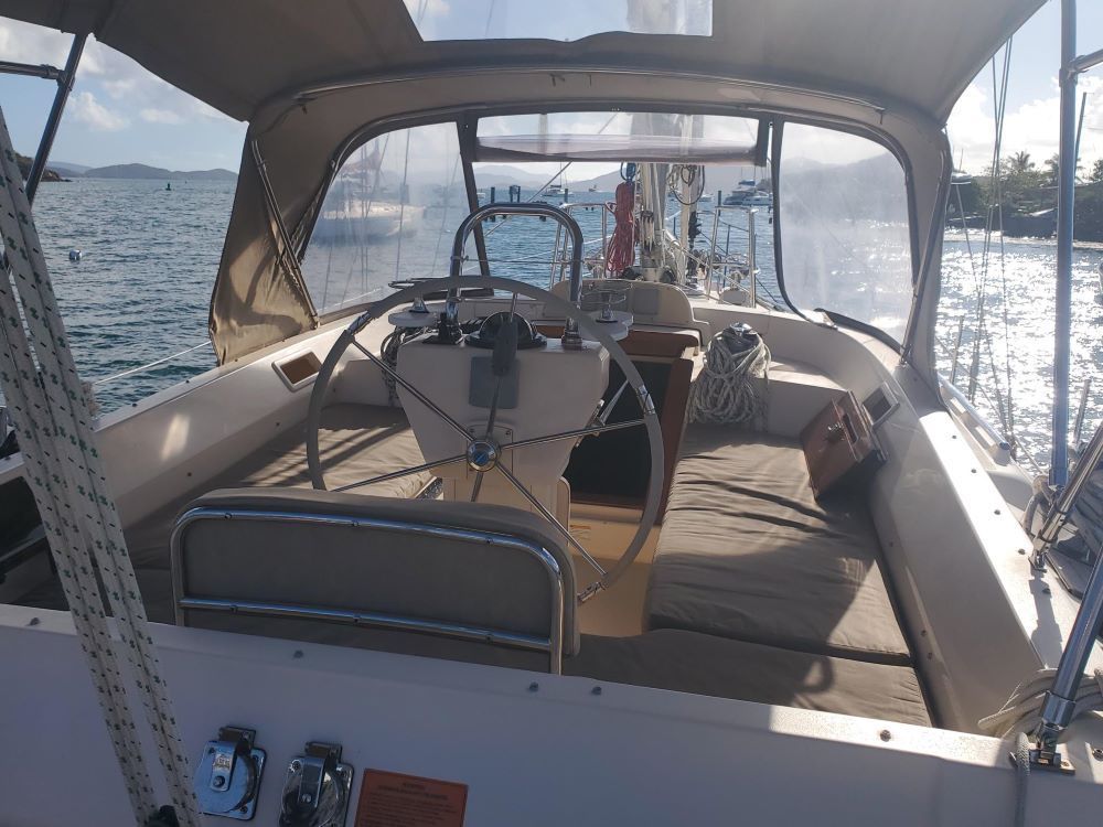 The inside of a sailboat with a steering wheel in the water.