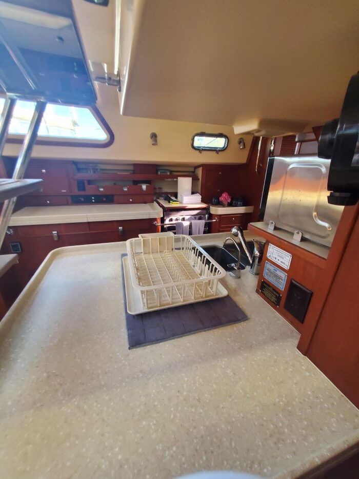 A kitchen on a boat with a sink , stove and microwave.