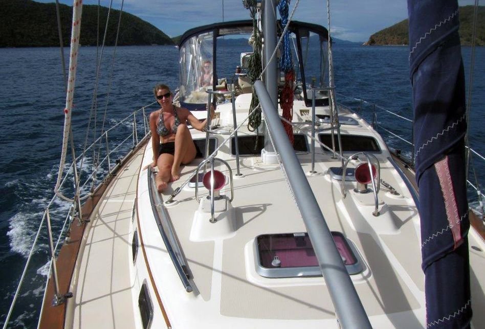 A woman sits on the deck of a sailboat in the ocean