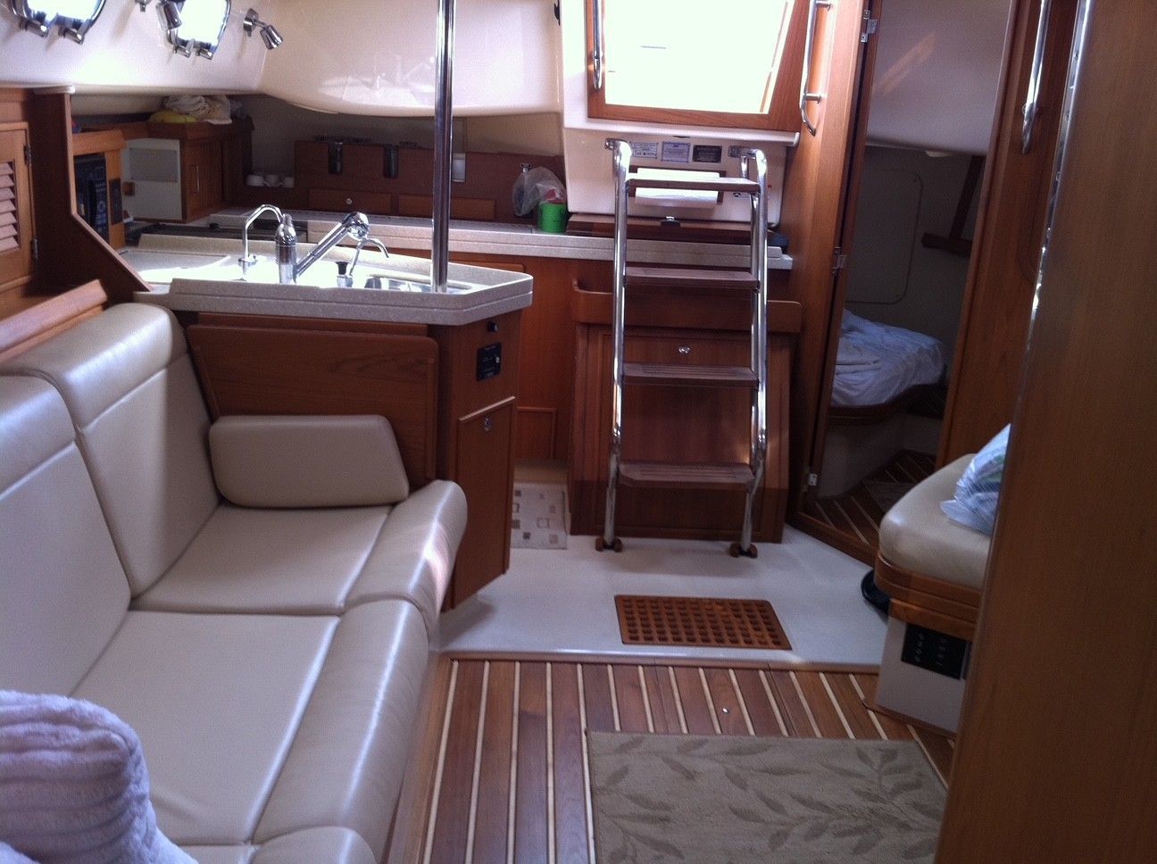 Interior of a boat cabin with a sofa, galley, and ladder leading to the deck.