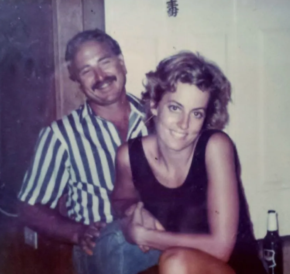 A man in a striped shirt is standing next to a woman in a black tank top