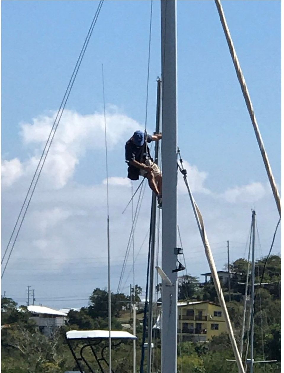 A man is climbing a pole on a sailboat