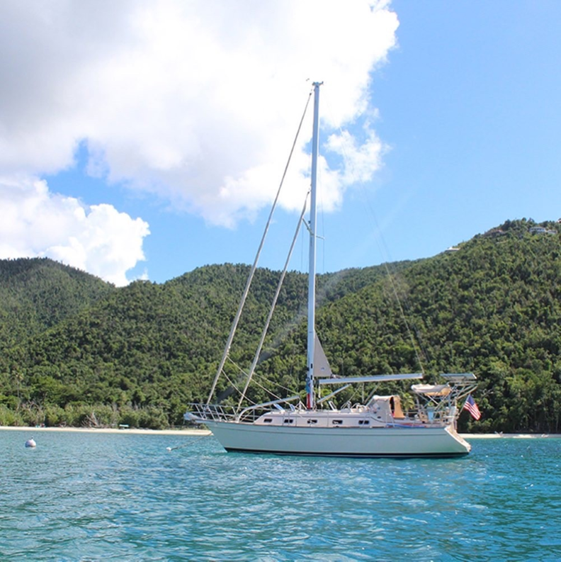 A sailboat is floating in the water near a beach