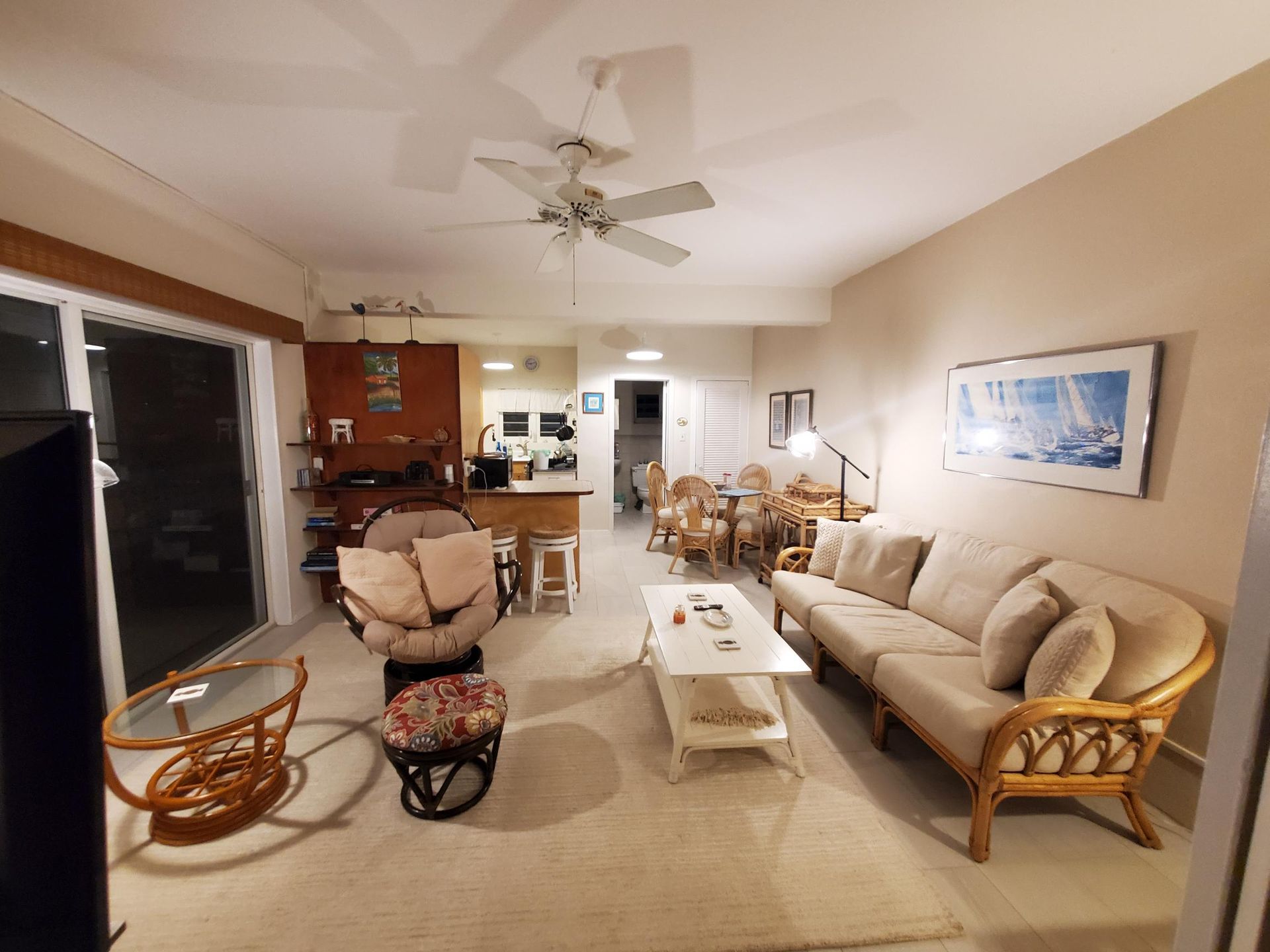 A living room with a couch and chairs and a ceiling fan