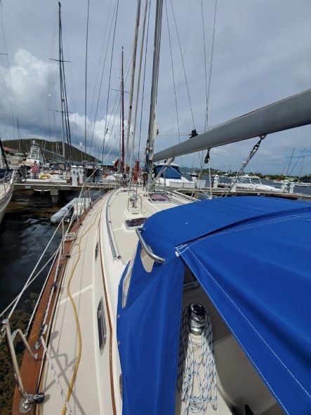 A sailboat with a blue cover is docked in a marina
