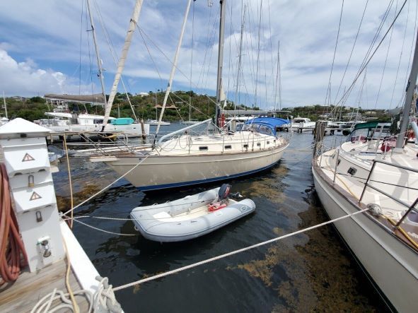 A small boat is docked next to a sailboat in a marina.