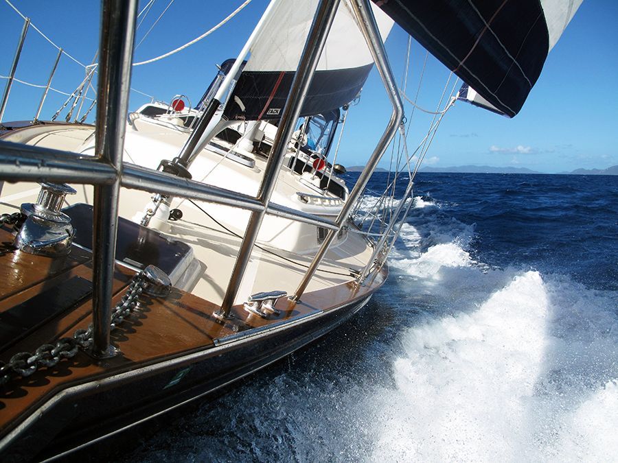 A sailboat is going through the ocean on a sunny day