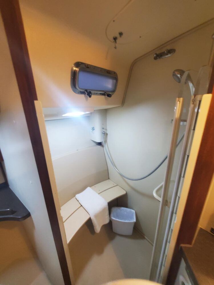 A bathroom with a shower and a trash can