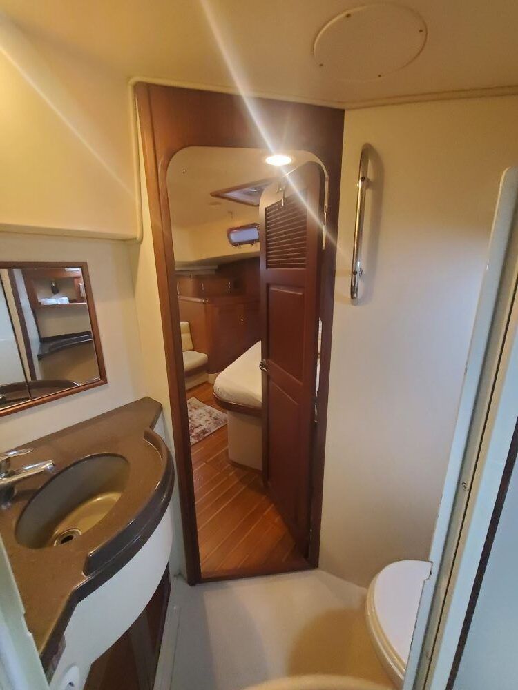 A bathroom on a boat with a sink , toilet and mirror.