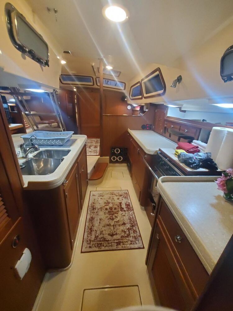 A kitchen on a boat with a rug on the floor.