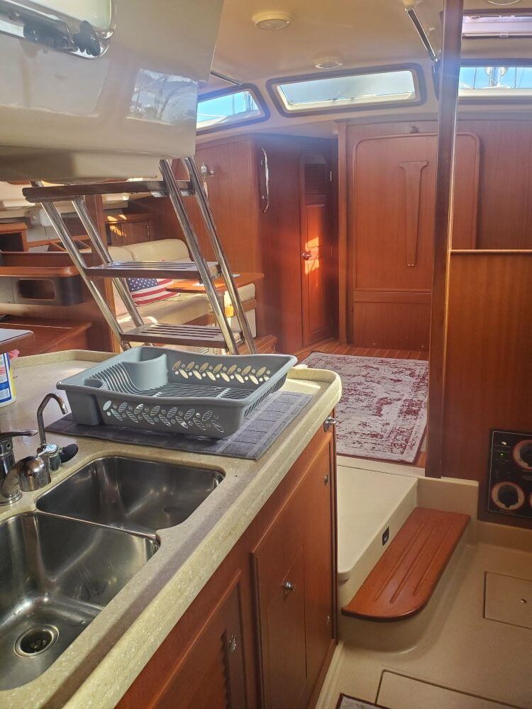 A kitchen on a boat with two sinks and a ladder.