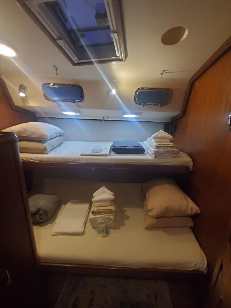 A bedroom on a boat with two beds and a skylight.