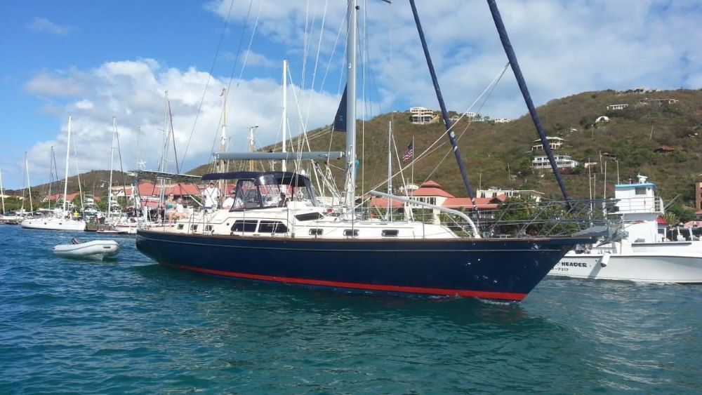 A large sailboat is docked in a harbor with other boats.