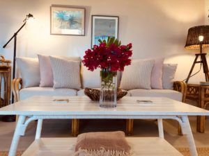 A living room with a couch and a coffee table with a vase of flowers on it.