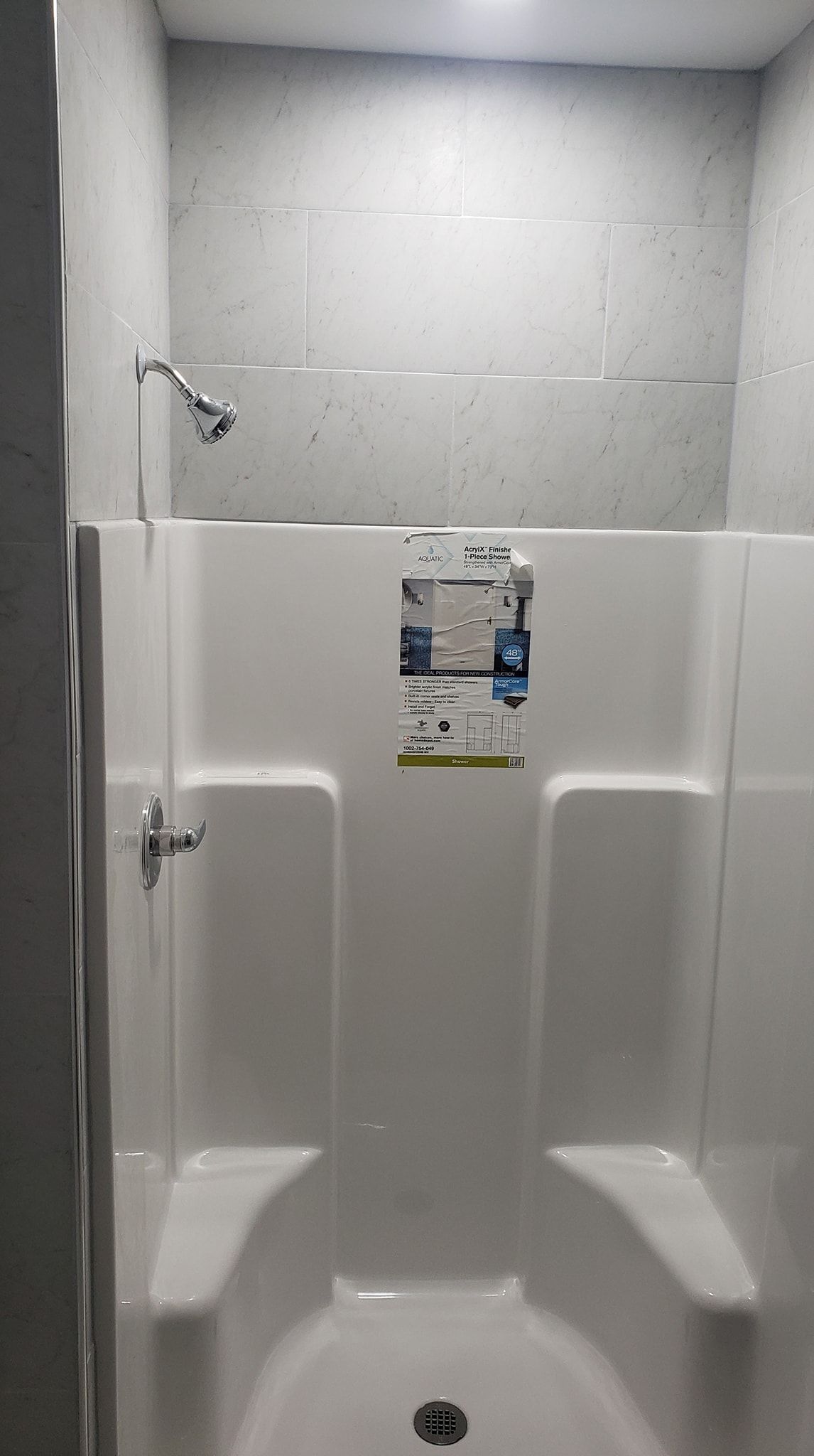 A white shower stall with a shower head in a bathroom.