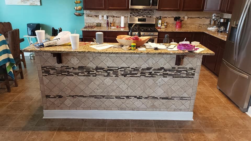 A kitchen with a large island and a stainless steel refrigerator.